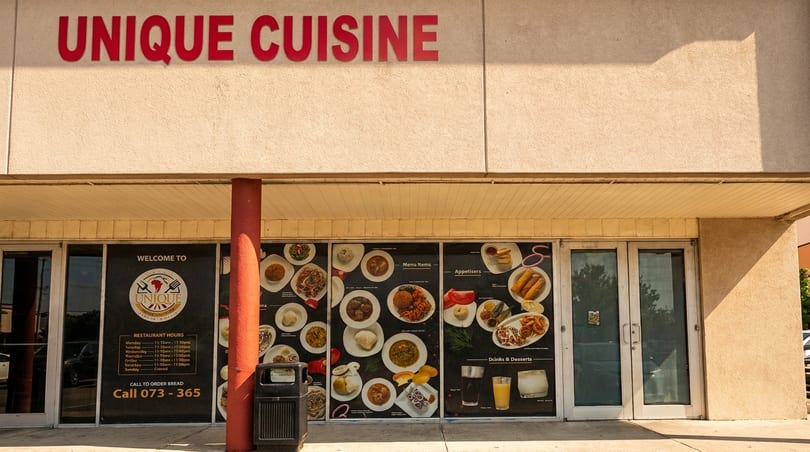 The exterior of Unique Cuisine restaurant with menu item photos displayed on the windows.